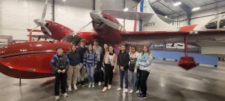 Students and teachers standing near historic aircraft.
