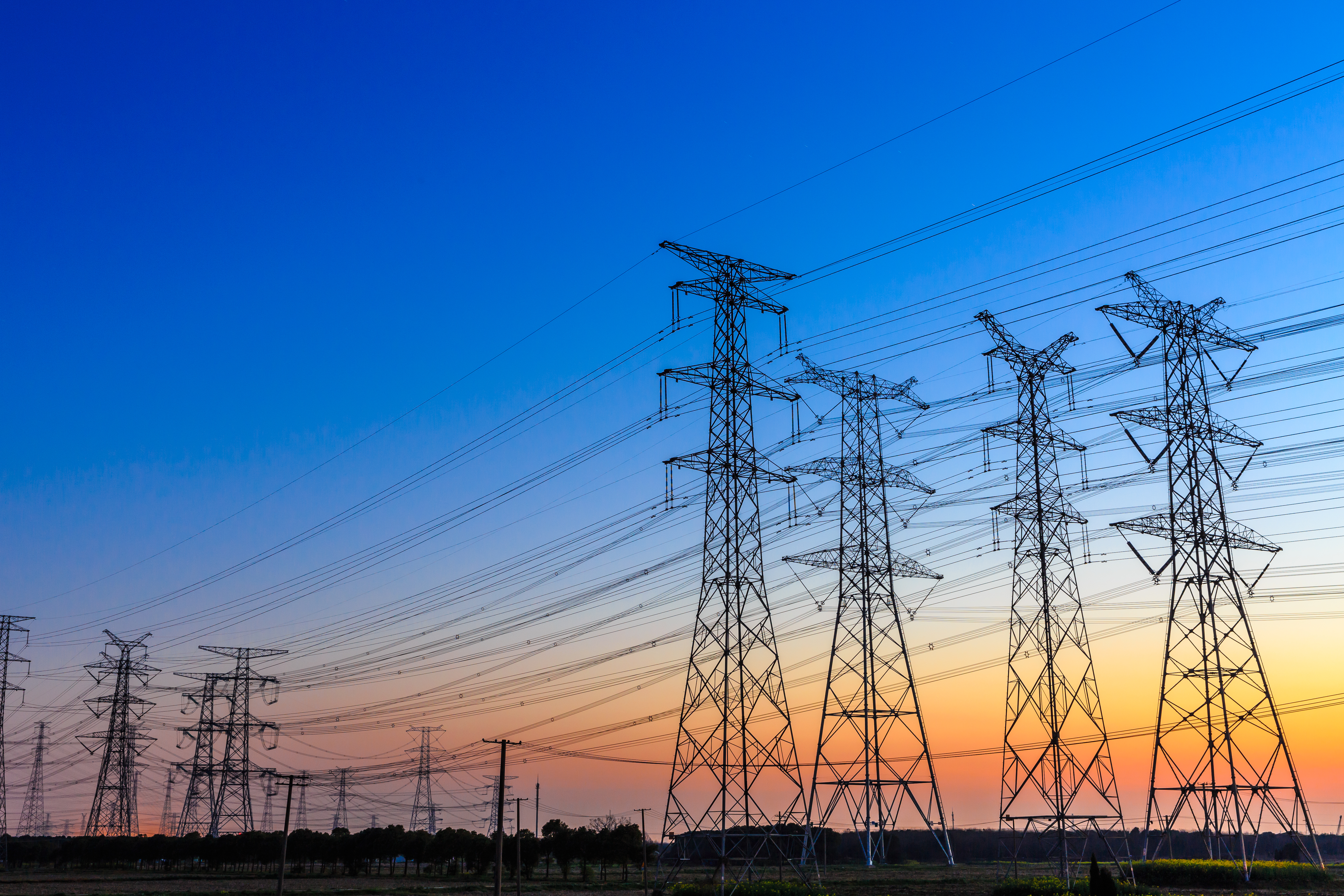 Group of high voltage power line towers at sunset