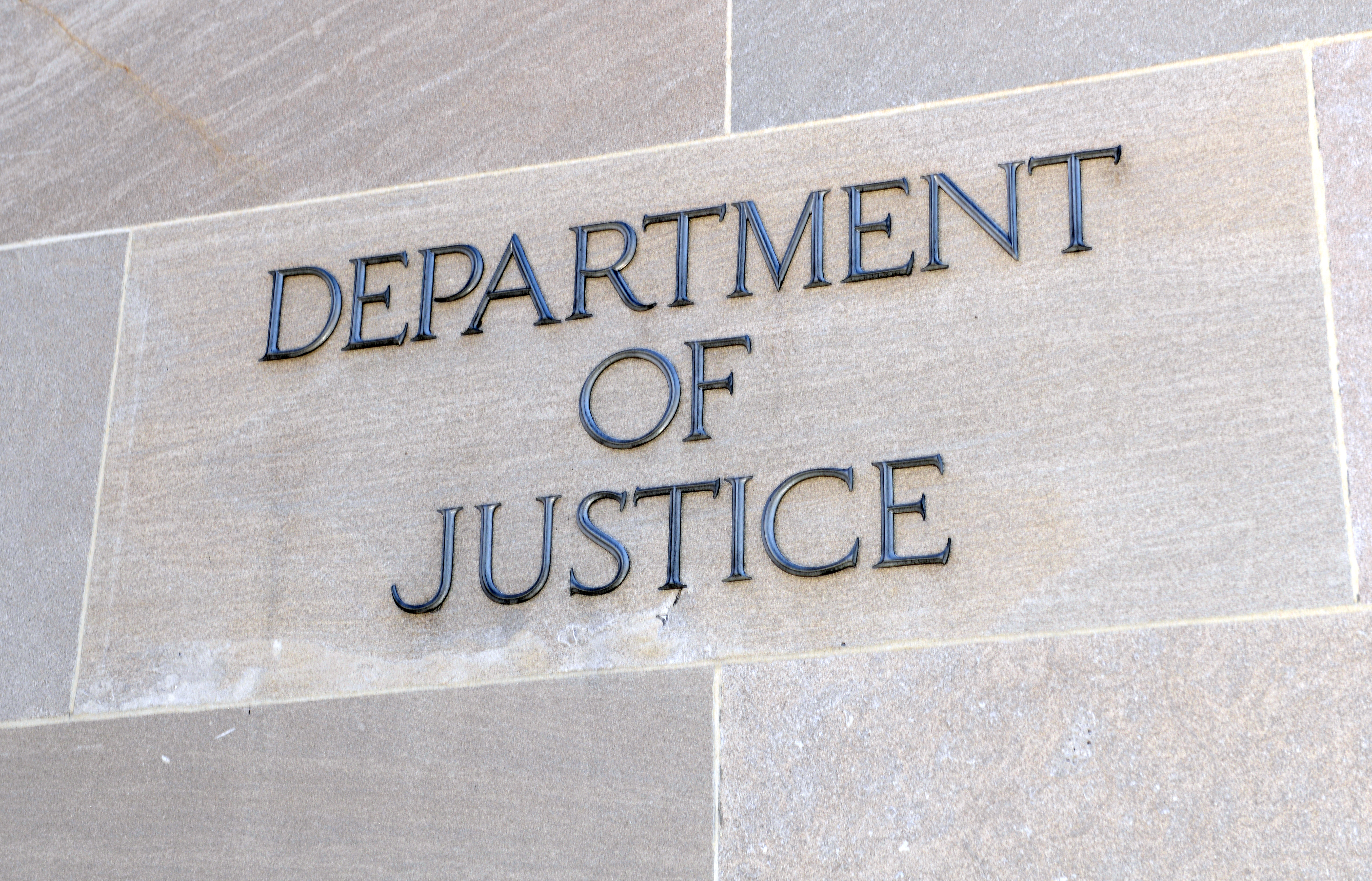 Sign on the side of a building reading "Department of Justice"