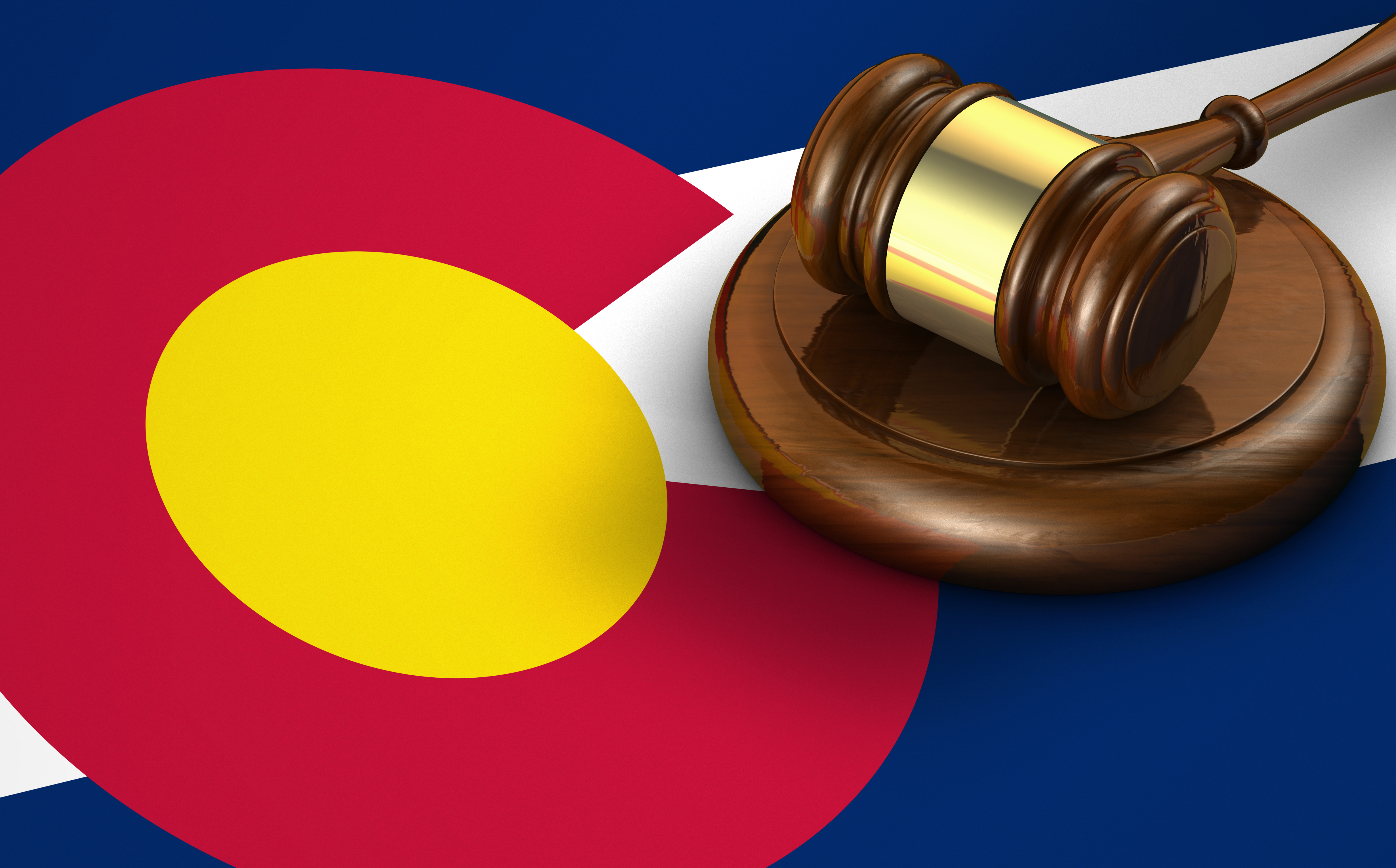 Gavel resting on a strike plate on top of a Colorado state flag.