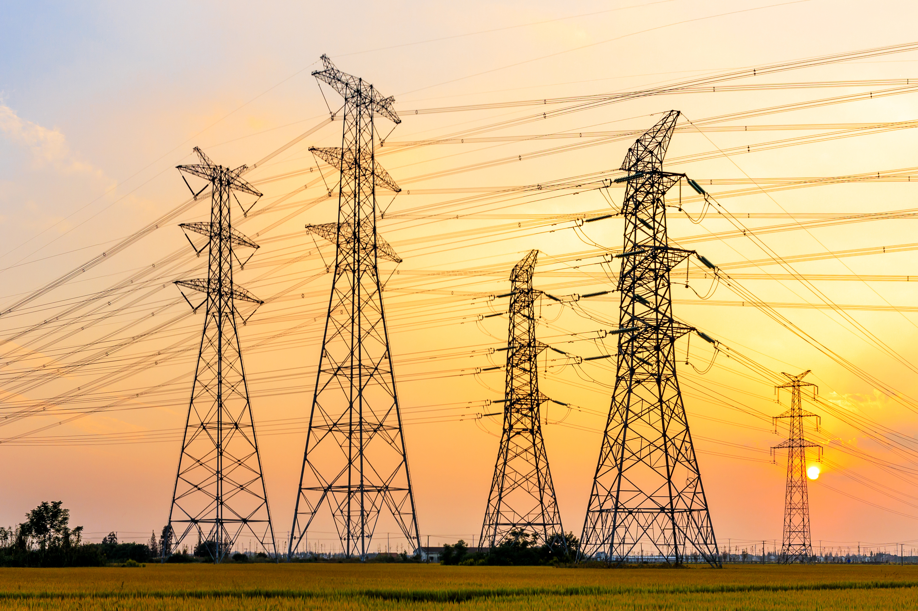 High voltage transmission towers stretching into the distance at sunrise/sunset