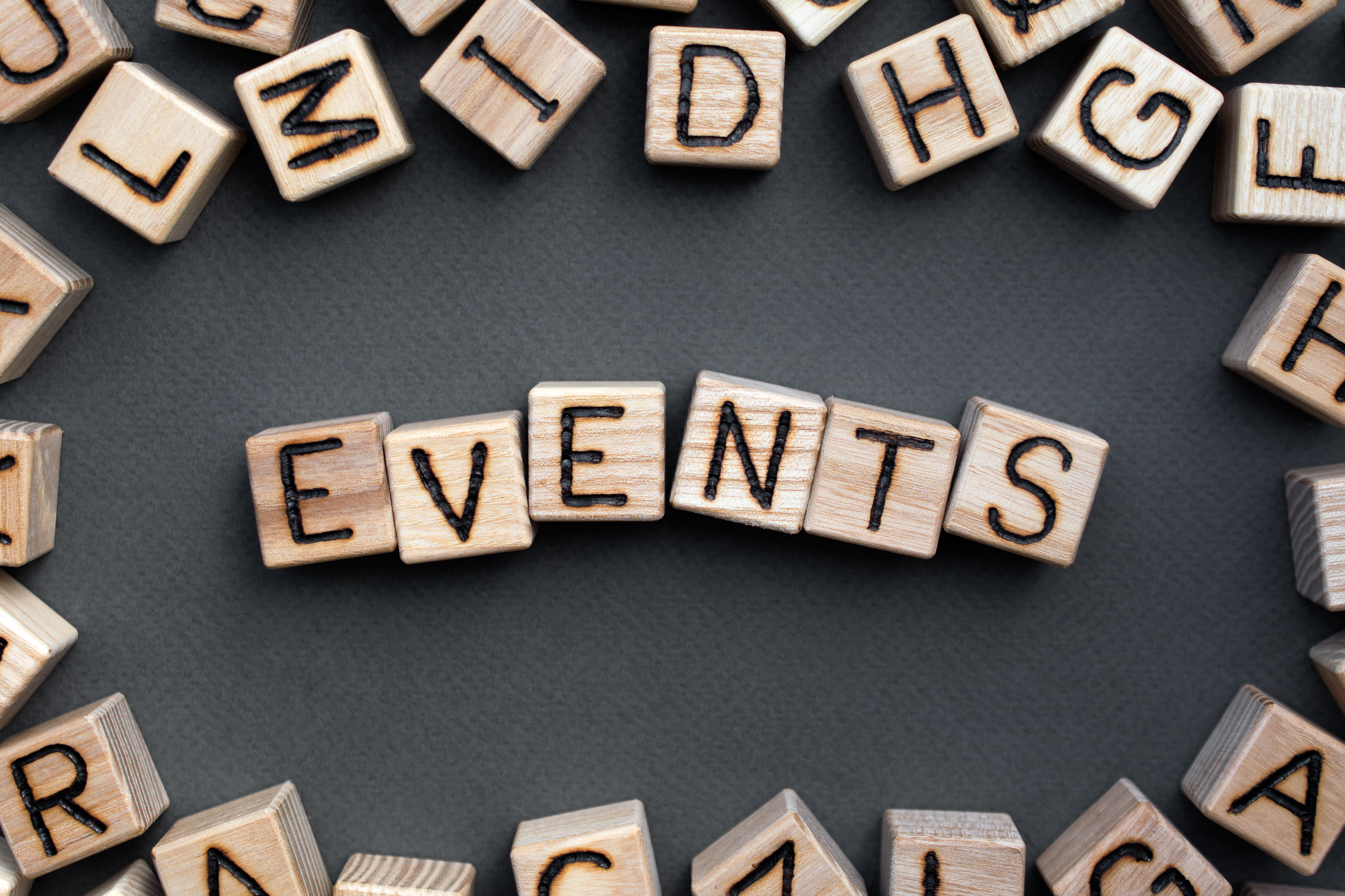 Assorted wooden block with letters on the sides, surrounding the word "events" on wooden blocks