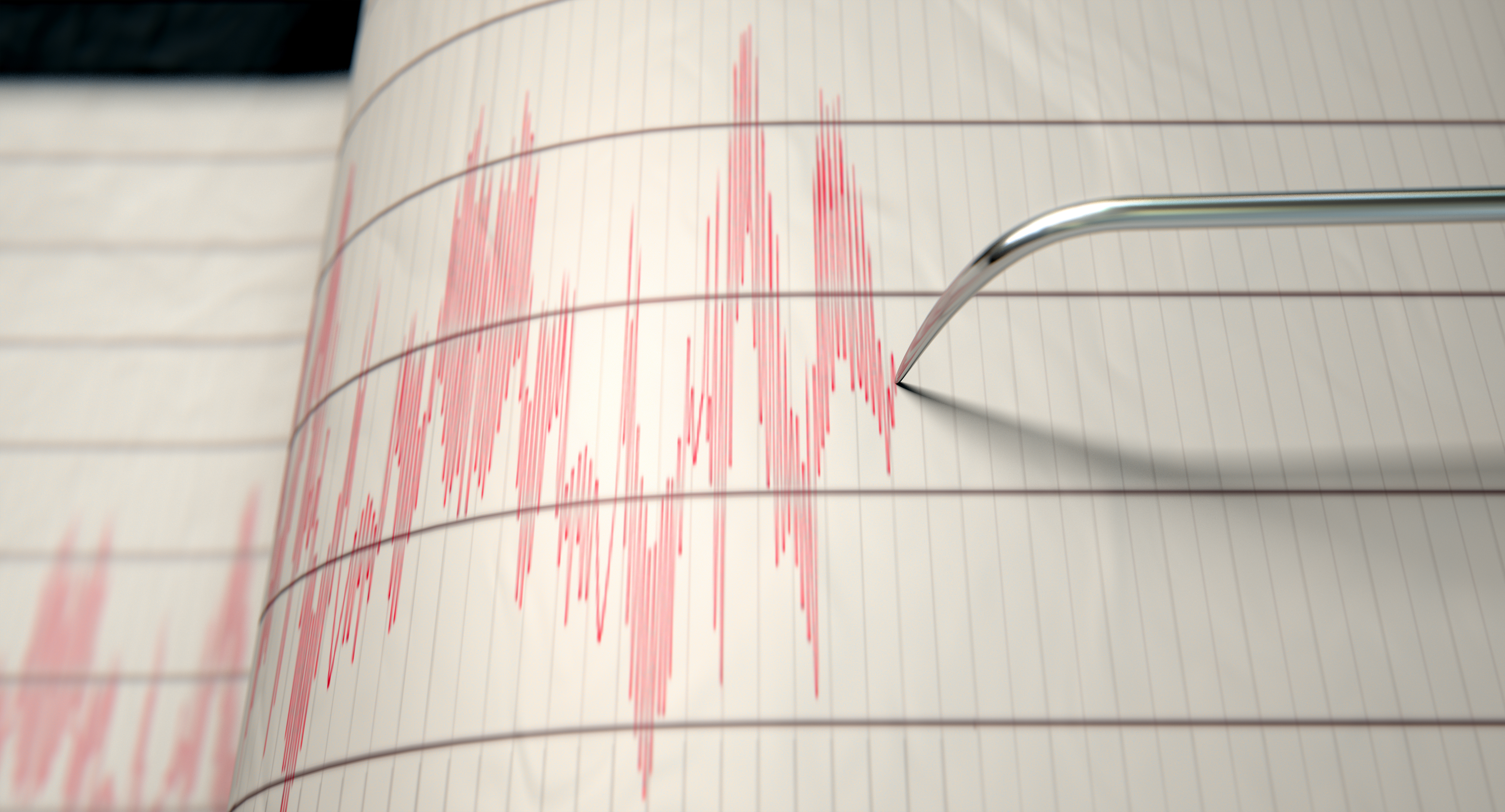 Earthquake seismograph paper with a stylus pen recording large activity variations.