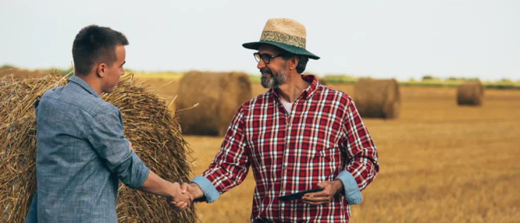 PICT Two people standing near a large hay bale - FamilyFeatures