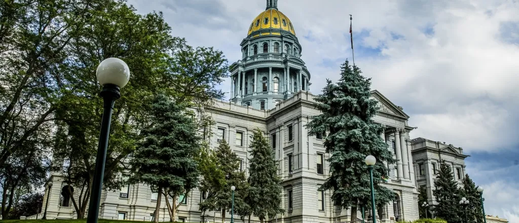 Colorado State Capitol building with green trees and golden dome.