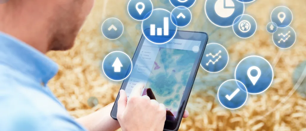 Person standing in a wheat field using a tablet device with agriculture icons imposed