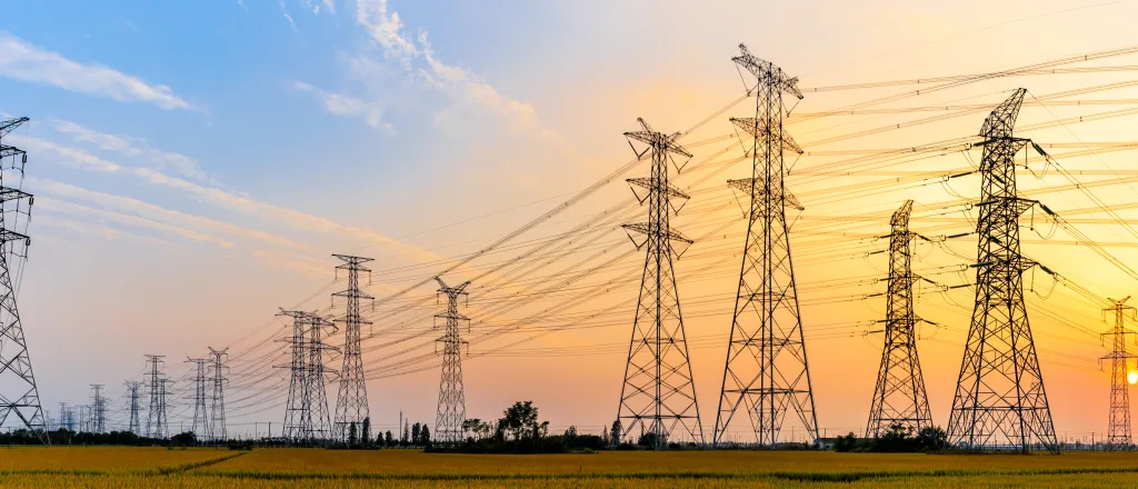 High voltage transmission towers stretching into the distance at sunrise/sunset