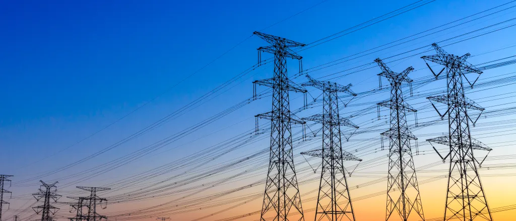 Group of high voltage power line towers at sunset