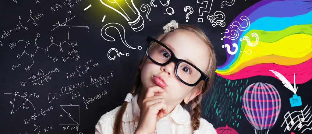 Child wearing glass with head tilted in an inquisitive pose in front of a chalkboard with colorful images