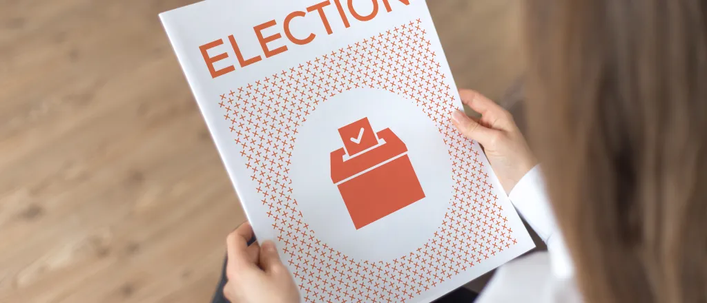 Person holding a booklet titled "Election"