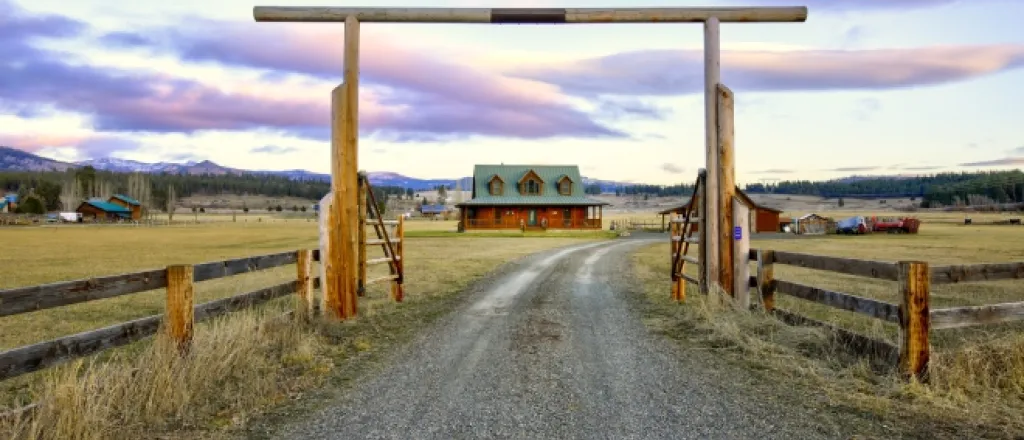 The gated entry at a beautiful, expansive ranch. There is a wood-built custom house on the property.