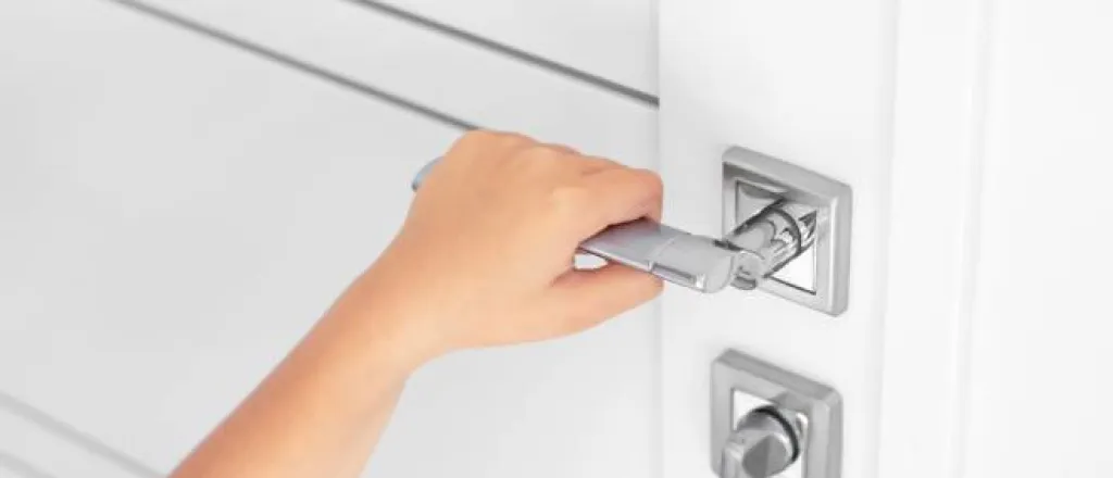 A child grabbing the door handle to an interior door. There is a bolted lock and they are trying to open the door.