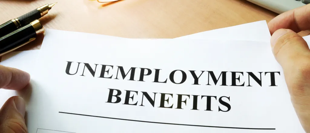 A form titled "Unemployment Benefits" on a desk near a calculator.