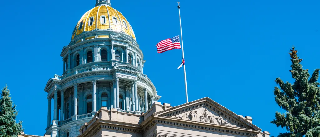 View of the Colorado state capitol entrance and dome, with United States and Colorado flags at half staff