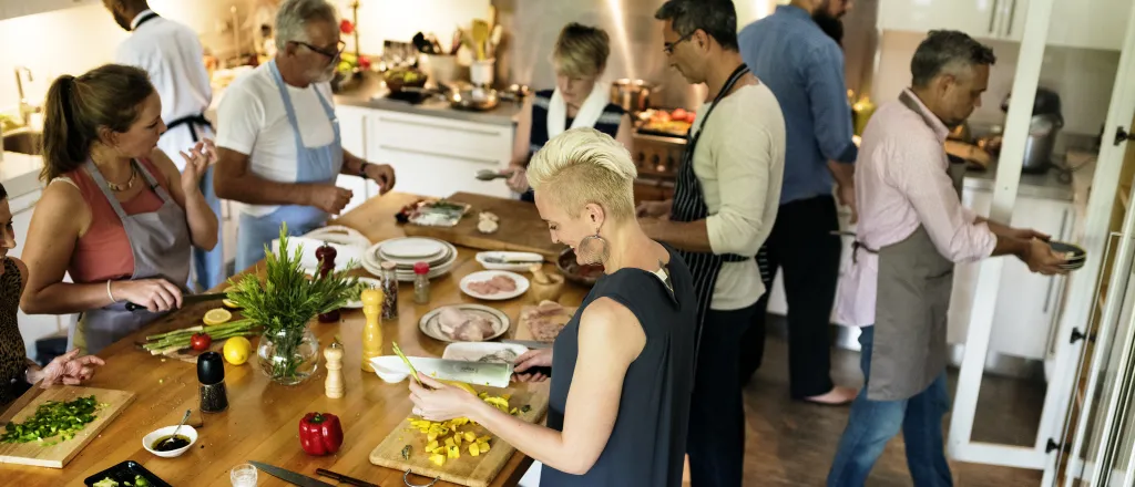 Numerous people in a large kitchen performing various cooking duties.