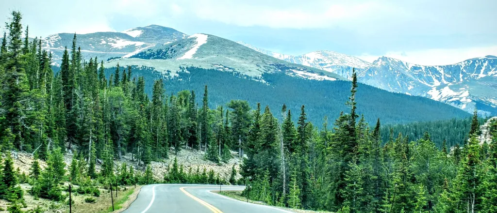 Winding two lane road in the foreground with Mount Blue Sky (formerly Mount Evans) Colorado in the backgrount