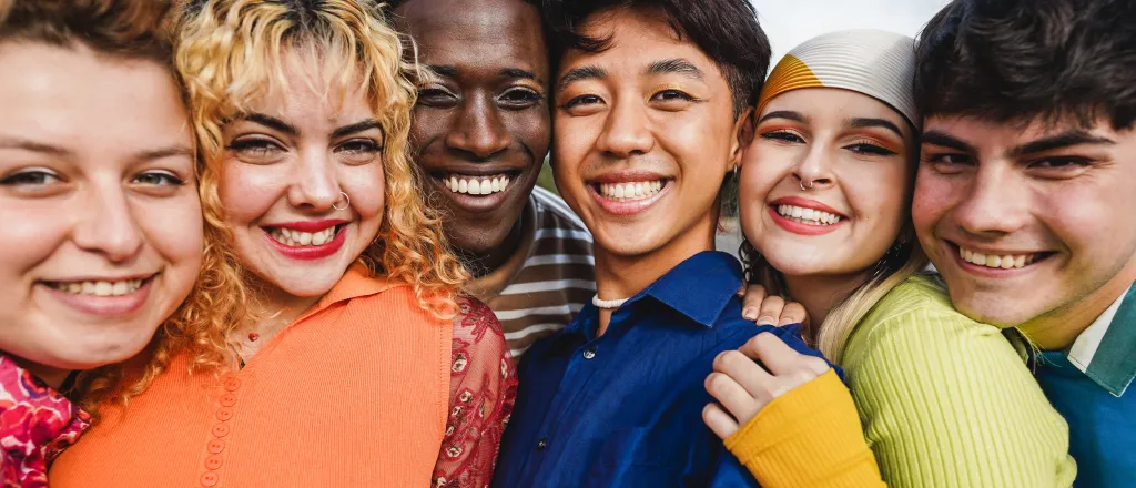 Diverse group of six young people standing close together smiling