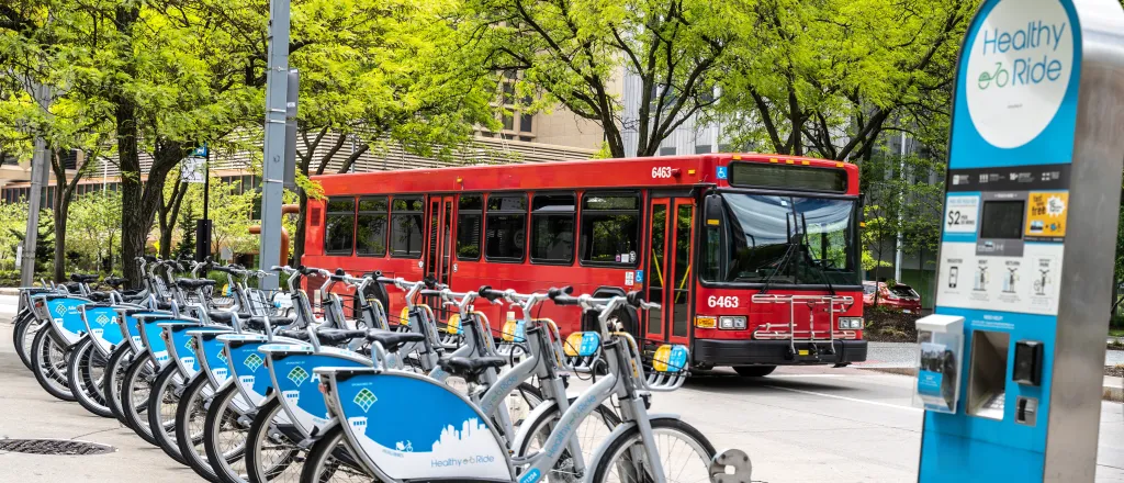 Row of electric bicycles for rent with a passenger bus in the background.