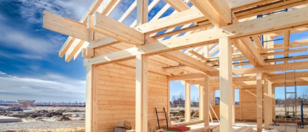 Common Tools You’ll Find on a New Home Build Site A new home build site with a variety of tools and wood stacked around the construction area. The sky is blue.