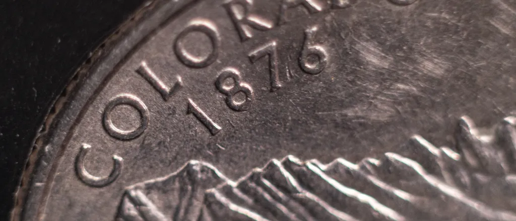 Closeup of a United States quarter coin showing "Colorado 1876"