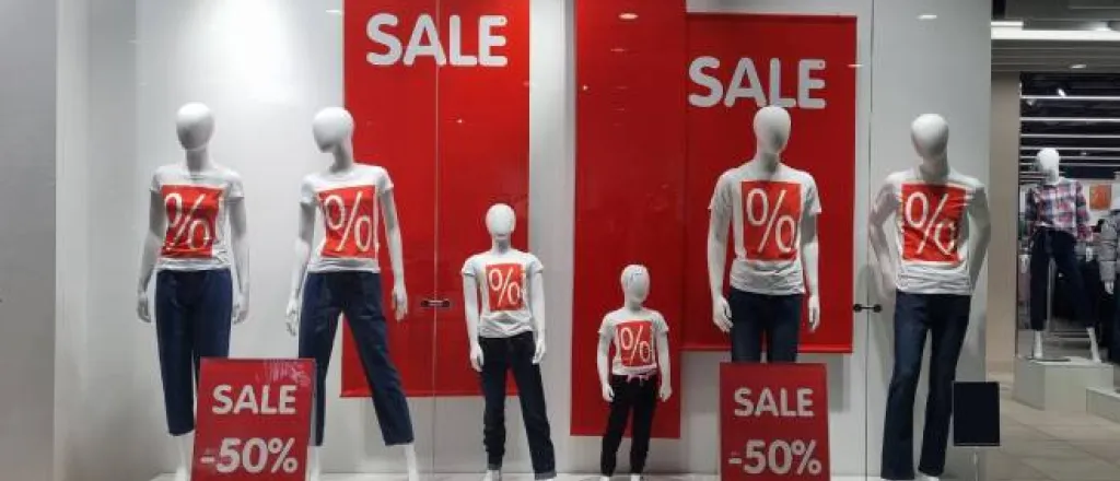 Manequins in white shirts with a red box with % signs in them surrounded by sale signs that advertise 50% off.