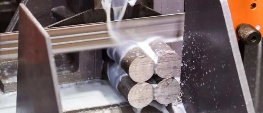An orange saw cuts four steel rods as creamy-looking liquid streams down over the rods and flows down a silver chute. An orange saw cuts four steel rods as creamy-looking liquid streams down over the rods and flows down a silver chute.