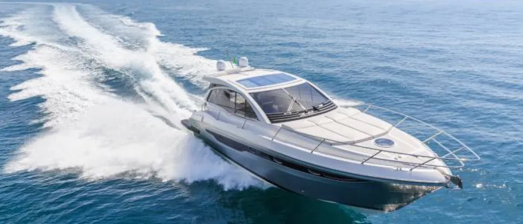 A blue and white luxury motorboat racing through a large body of water and leaving a wake behind it.