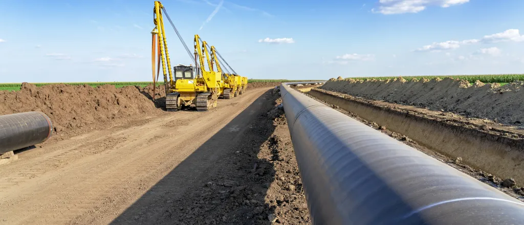 PROMO HIRES Energy - Oil Gas Pipeline Construction Machinery Equipment - iStock - RGtimeline Pipeline being buried with heavy equipment in the background.