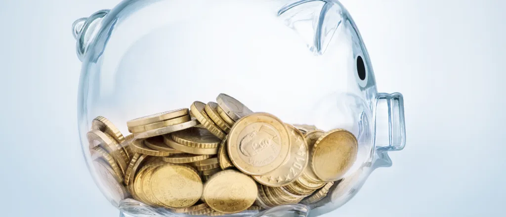 PROMO HIRES Finance - Glass Piggy Bank with Coins - Pogonici - iStock Glass piggy bank half filled with gold coins