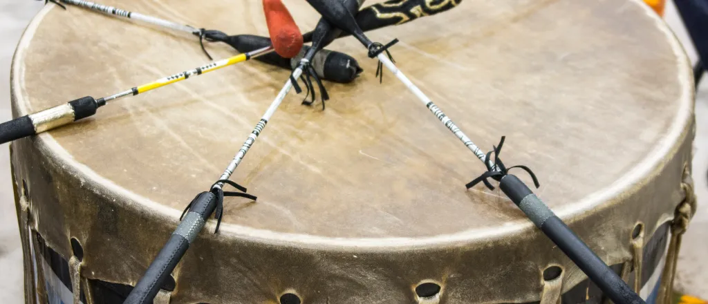 PROMO HIRES Indigenous - Drum Native American Tribe Tribal First Nations - iStock - Woodkern Indigenous wood and animal skin drum with six drumsticks resting on top