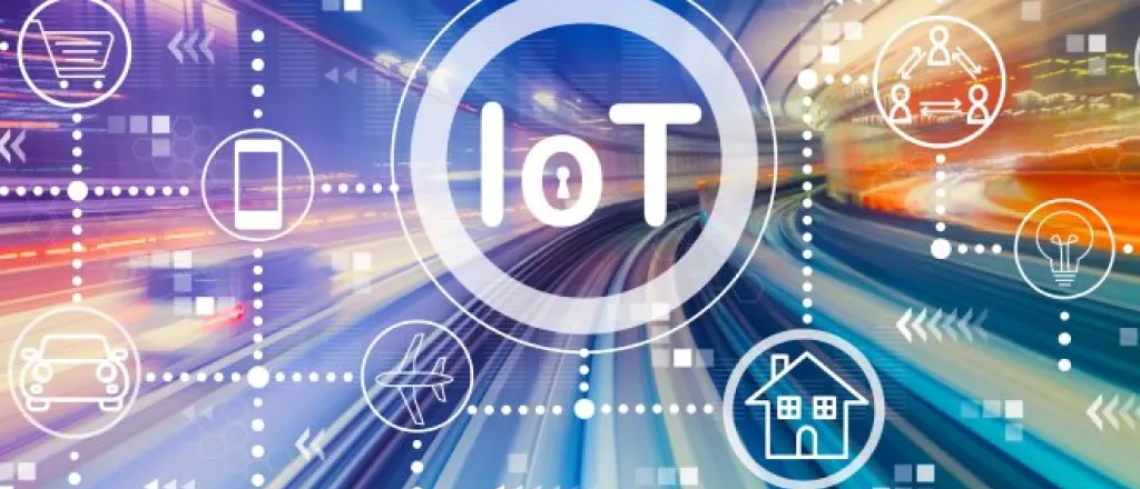A blurred road with colorful lighting and a superimposed graphic of different IoT symbols and the acronym "IoT" in the middle.
