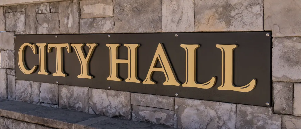 Close up of a cut stone wall. A sign affixed to the wall had the words "City Hall"