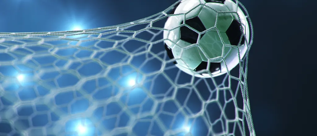 PROMO HIRES CROPPED Sports - Soccer Ball Net Goal - Rost-9D - iStock-1487218062 Soccer ball/football stretching the goal net with stadium lights in the background.
