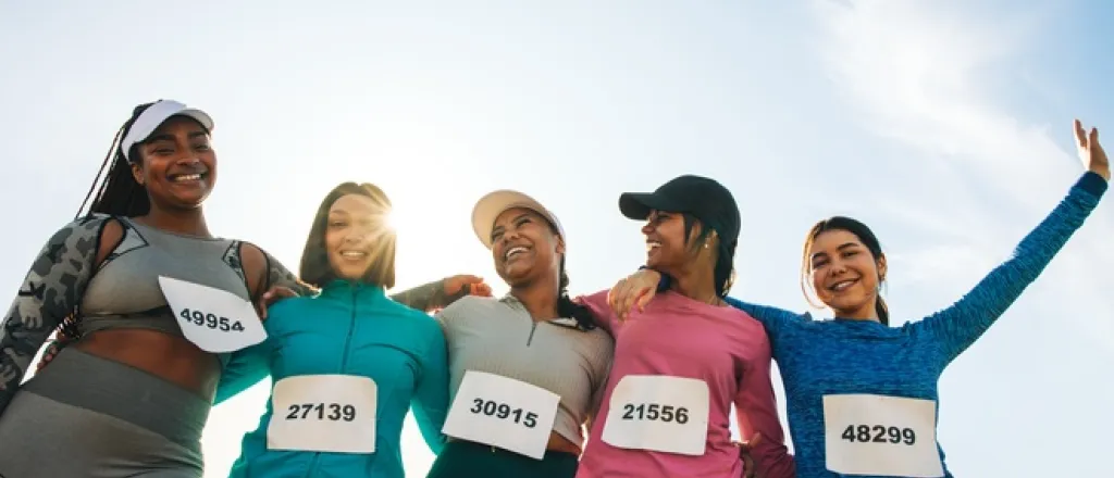 A group of diverse women is celebrating before or after a sporting competition. They're all smiling and laughing.