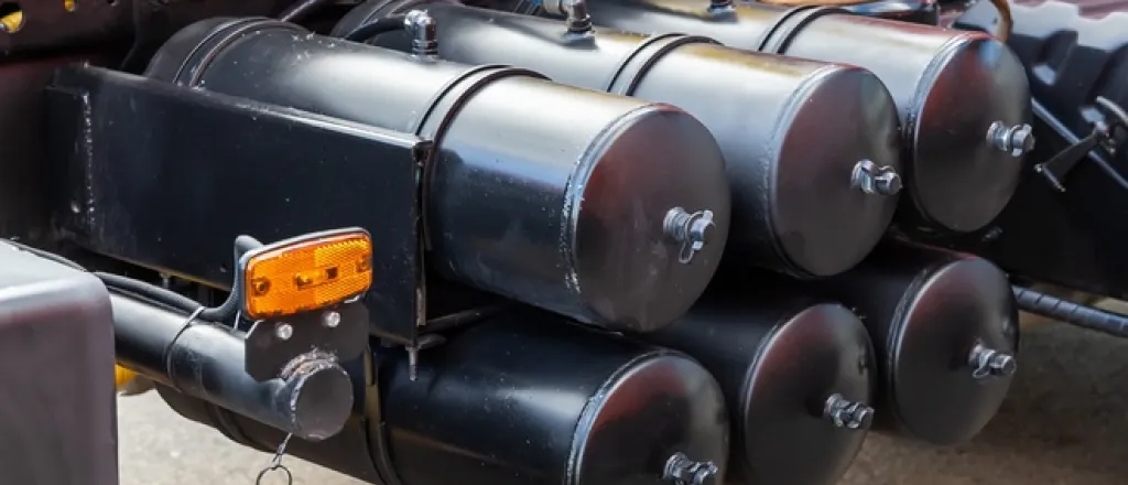 Six air cylinder tanks in a brake system are at close range. They're situated underneath a heavy-duty truck.
