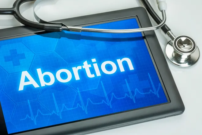 Computer tablet displaying the word "Abortion" with a stethoscope draped over the corner