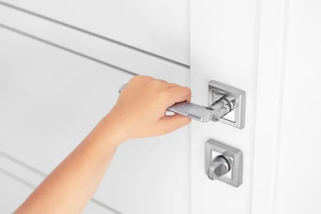 A child grabbing the door handle to an interior door. There is a bolted lock and they are trying to open the door.