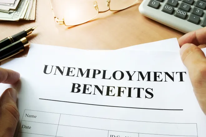 A form titled "Unemployment Benefits" on a desk near a calculator.