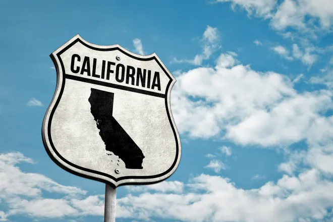 Road sign with the word "California" and a silhouette of the state. A cloudy sky is in the background.