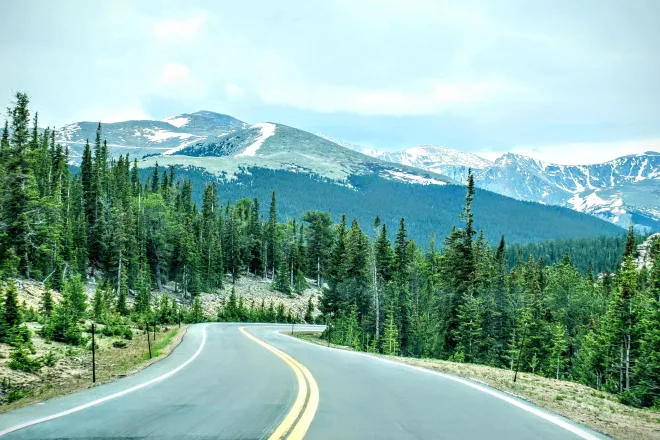 Winding two lane road in the foreground with Mount Blue Sky (formerly Mount Evans) Colorado in the backgrount