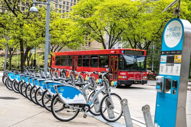 Row of electric bicycles for rent with a passenger bus in the background.