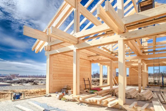 A new home build site with a variety of tools and wood stacked around the construction area. The sky is blue.