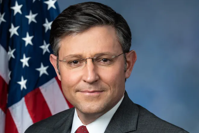 Head photo of politician Mike Johnson. A United States flag is in the background.