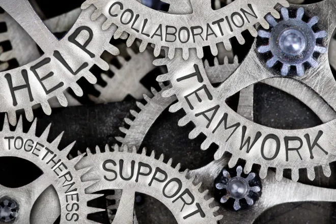 Interlocking machinery gears with the words "help, collaboration, teamwork, support, and togetherness" stamped on the side
