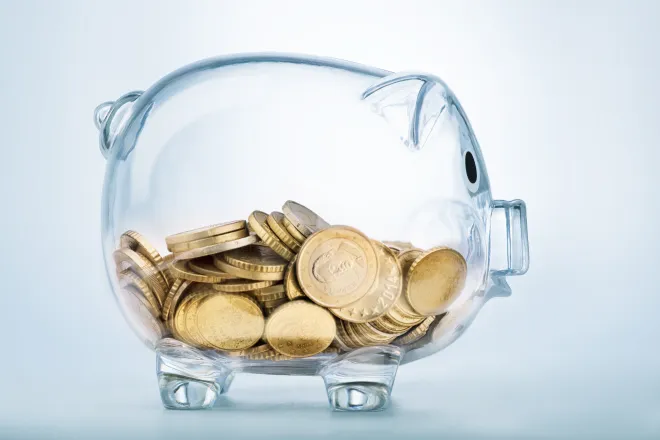 Glass piggy bank half filled with gold coins