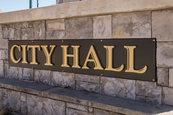 Close up of a cut stone wall. A sign affixed to the wall had the words "City Hall"