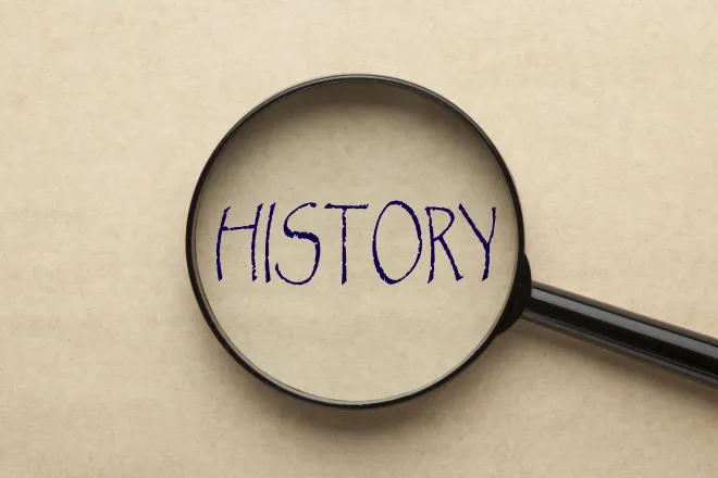 Overhead view of a magnifying glass over the word "history."