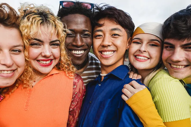 Diverse group of six young people standing close together smiling