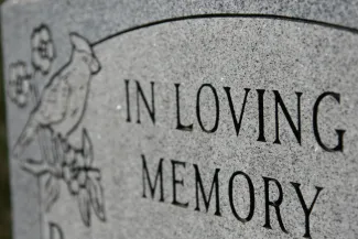 Grave marker inscribed with 'In Loving Memory' - iStock - melissarobison