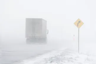 PROMO HIRES Weather - Truck Road Sign Snow Blizzard - lloydmp - iStock-145131807 Semi truck on a snow-covered road